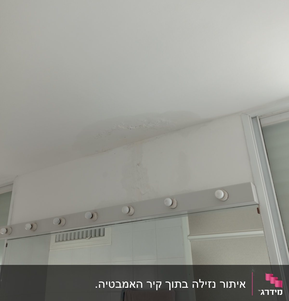 כתם רטיבות בתקרה מעל מראה בחדר אמבטיה